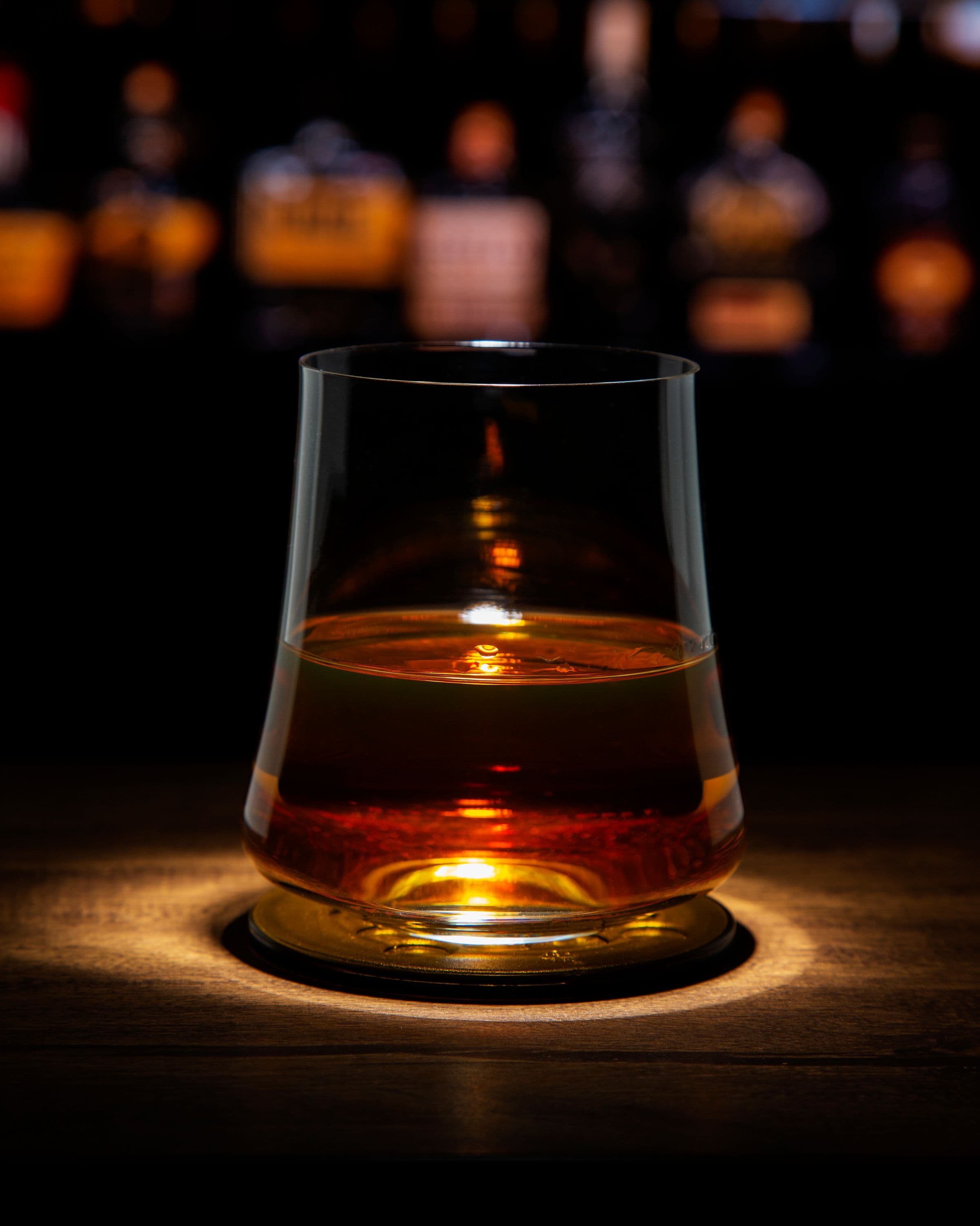 A neat pour of bourbon in a tasting glass on a bar